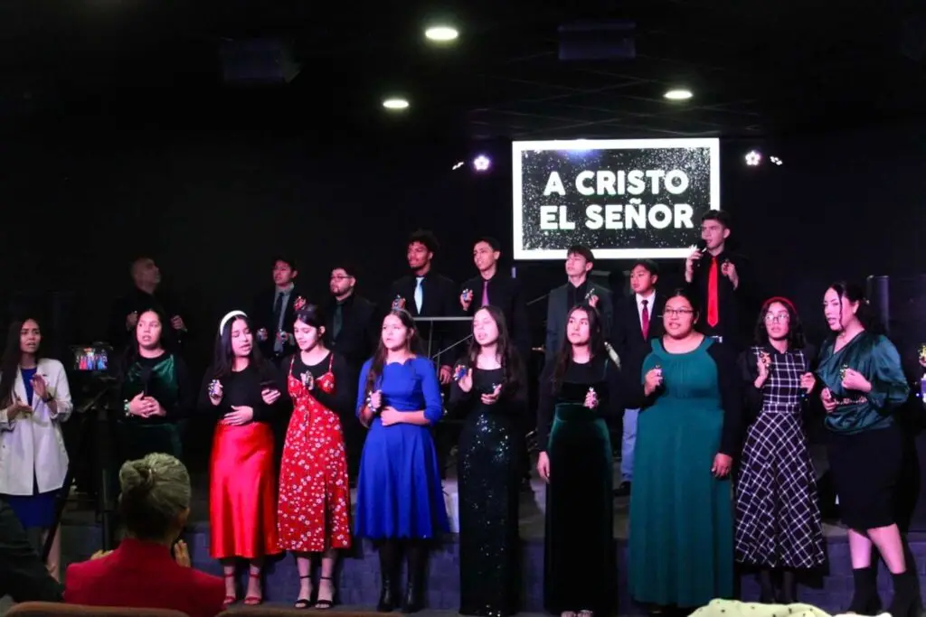 Grupo de jóvenes en el escenario de la iglesia Firstborn Ministerios en Rockford, IL, adorando y cantando a Cristo el Señor durante un servicio especial.